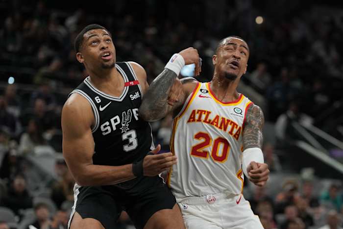 San Antonio Spurs forward Keldon Johnson and Atlanta Hawks forward John Collins battle for a rebound.